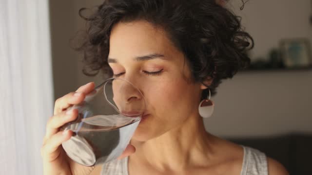 A Woman Drinks Water From A Glass